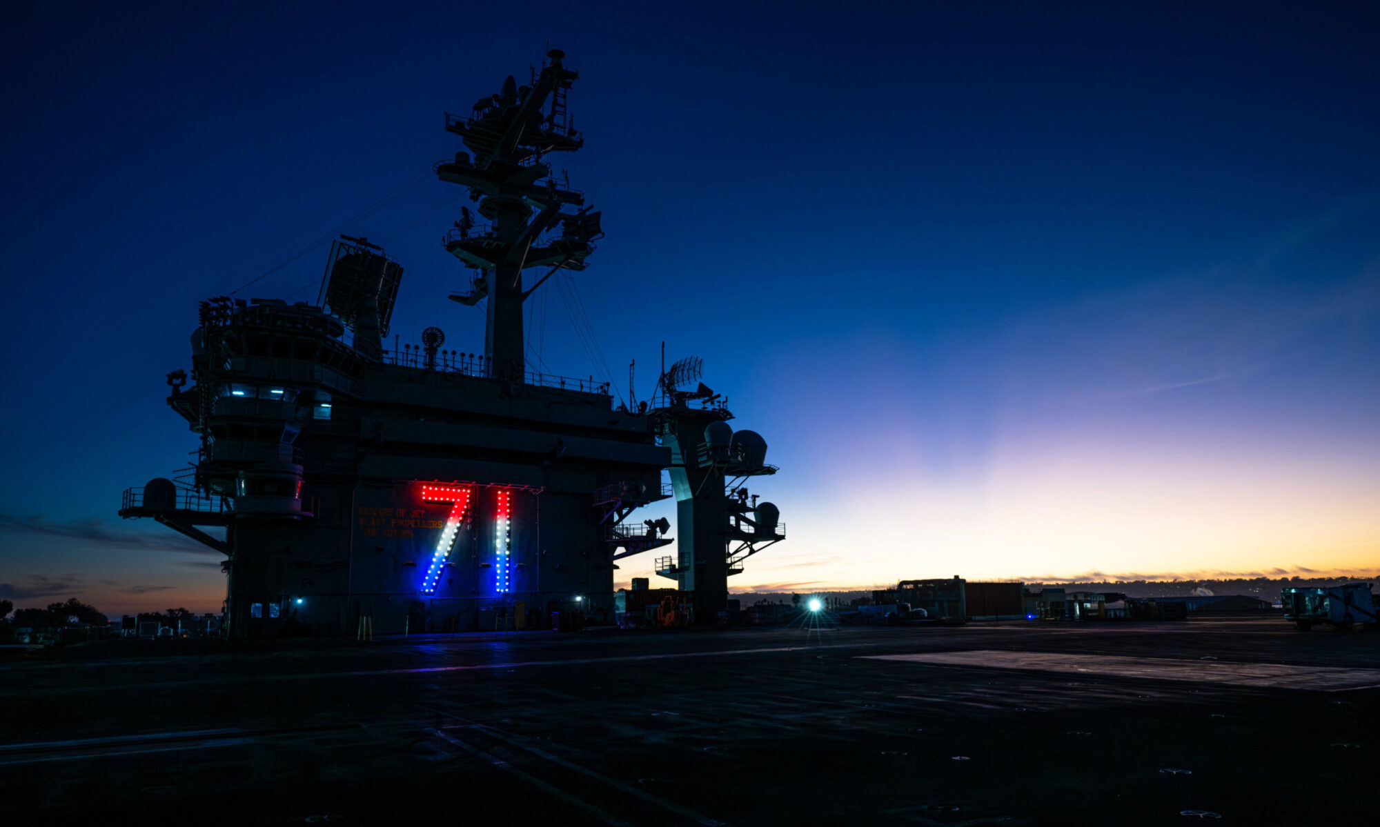 The sun sets behind the Nimitz-class aircraft carrier USS Theodore Roosevelt (CVN 71), Oct. 22, 2024. Theodore Roosevelt, the flagship of Theodore Roosevelt Carrier Strike Group, is currently pierside at Naval Air Station North Island in its homeport of San Diego.