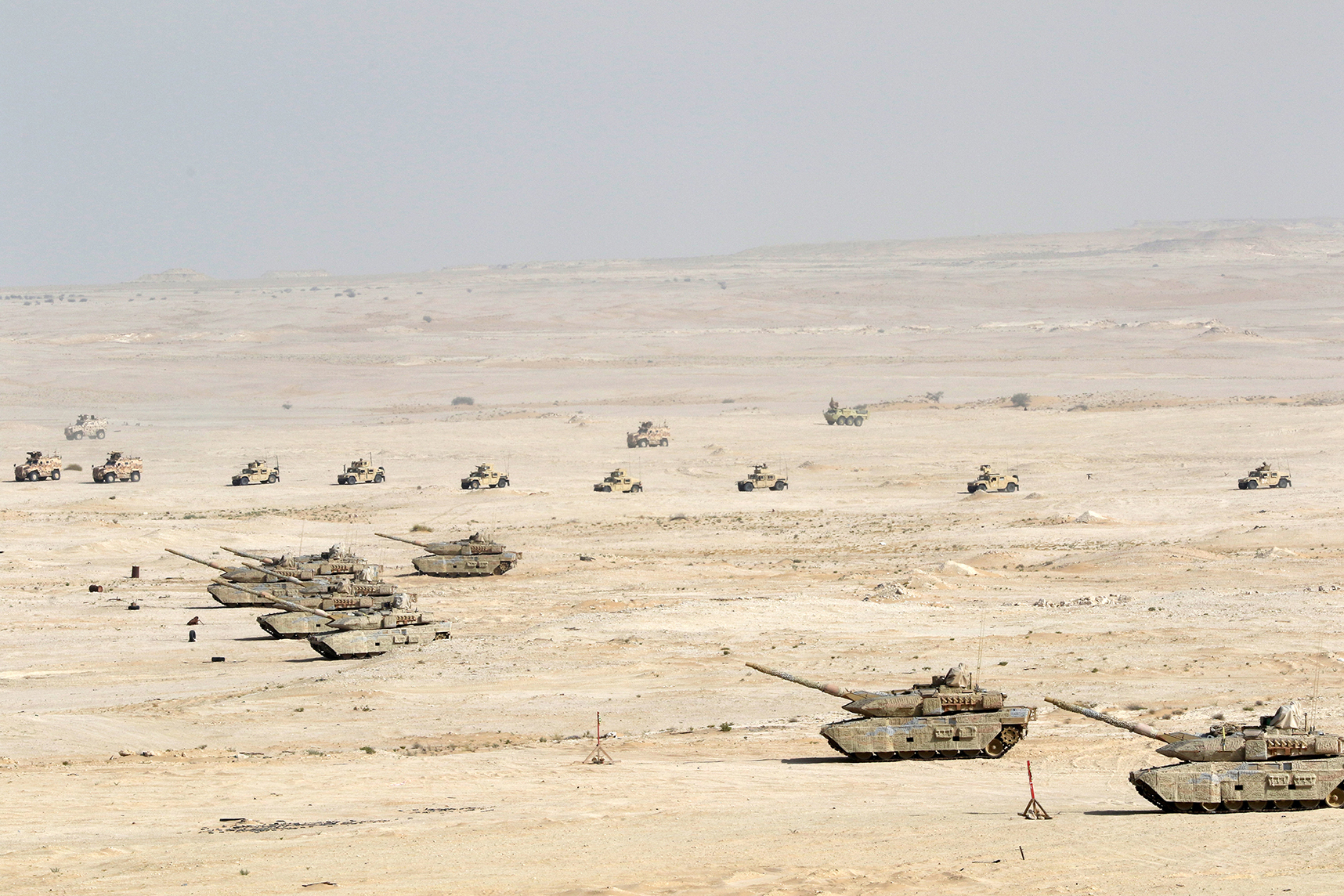 A platoon of Task Force Spartan Soldiers moves their Humvees, center of photo, into place between Qatari tanks and armored vehicles during a combined arms live fire exercise on June 1, 2023 at Al Qalayel Training Area, Qatar. Soldiers with Task Force Spartan and the Qatar Emiri Forces trained together from mid-May to early June for the 2023 Al Adheed exercise. (U.S. Army National Guard photo by Master Sgt. Doug Roles.)