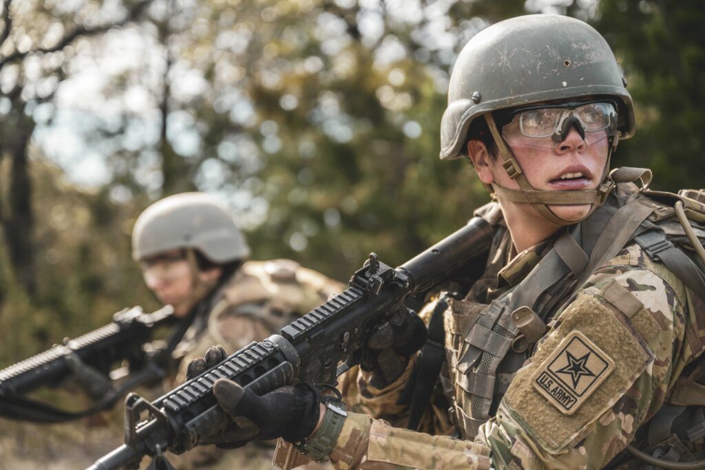 A private and U.S. Army Medical Center of Excellence combat medic specialist listens to instruction from the team leader while patrolling during a combat medic field training exercise at Joint Base San Antonio-Camp Bullis, Texas, Jan. 25, 2024. The purpose of the course is to expand upon Army medic base level skills on how to keep casualties of combat operations alive for 12-24 hours after engagement. After a threat is neutralized while on patrol, the soldiers transport the wounded to the nearest battalion aid station at the forward operating base to continue emergency care. (U.S. Air Force photo by Taylor Curry.)